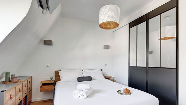 A modern bedroom with a bed, bedside tables, a dresser, and a large window. - Champs-Élysées - 1BR (Paris)