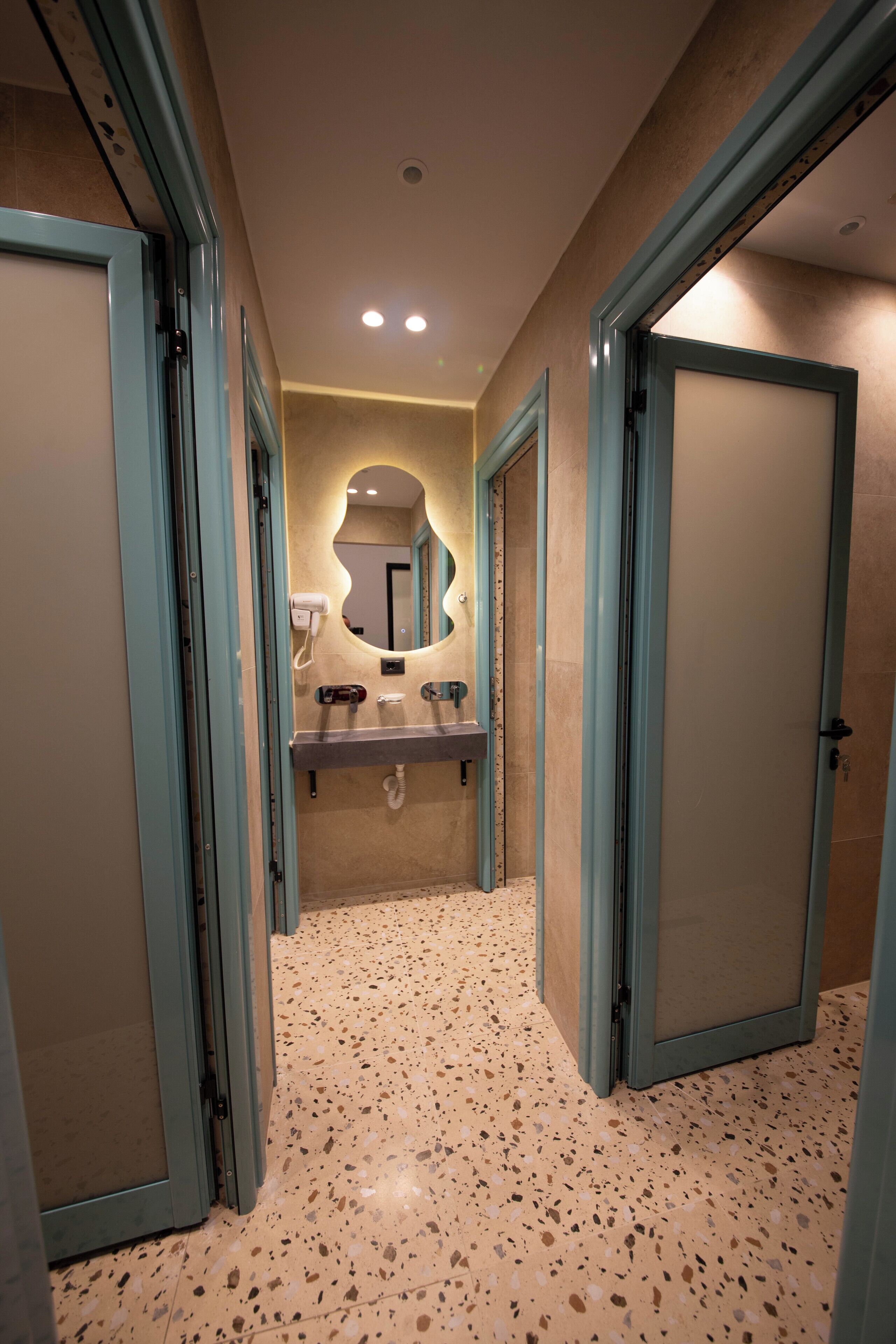 A hallway with a speckled floor, a mirror, and a sink.
