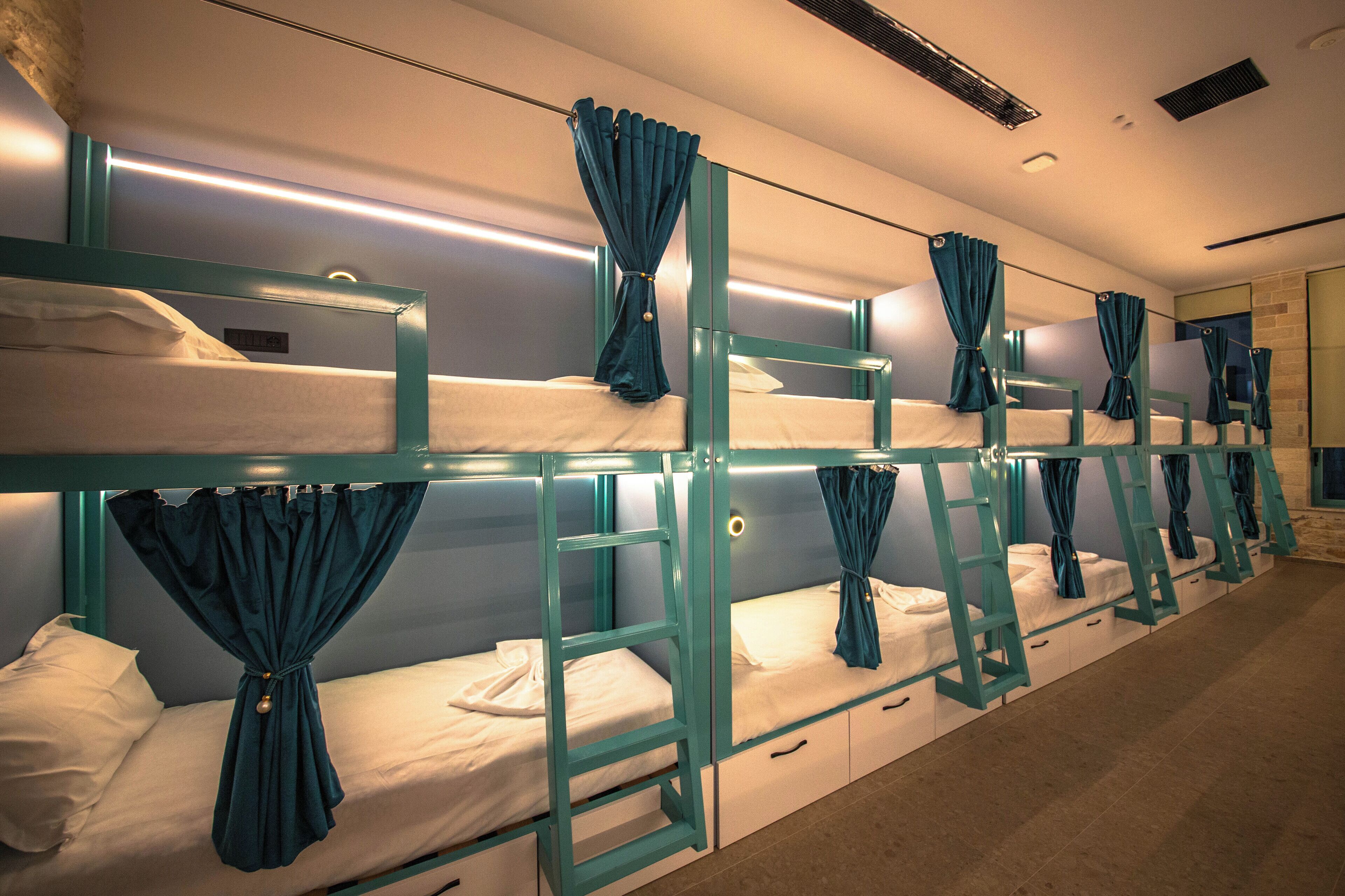 A row of bunk beds with curtains, each bed having a ladder and a small drawer.