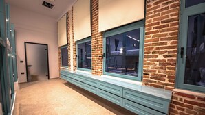 A hallway with a brick wall, large windows, and a light blue bench. - Vega 43 Hostel (Sarande)