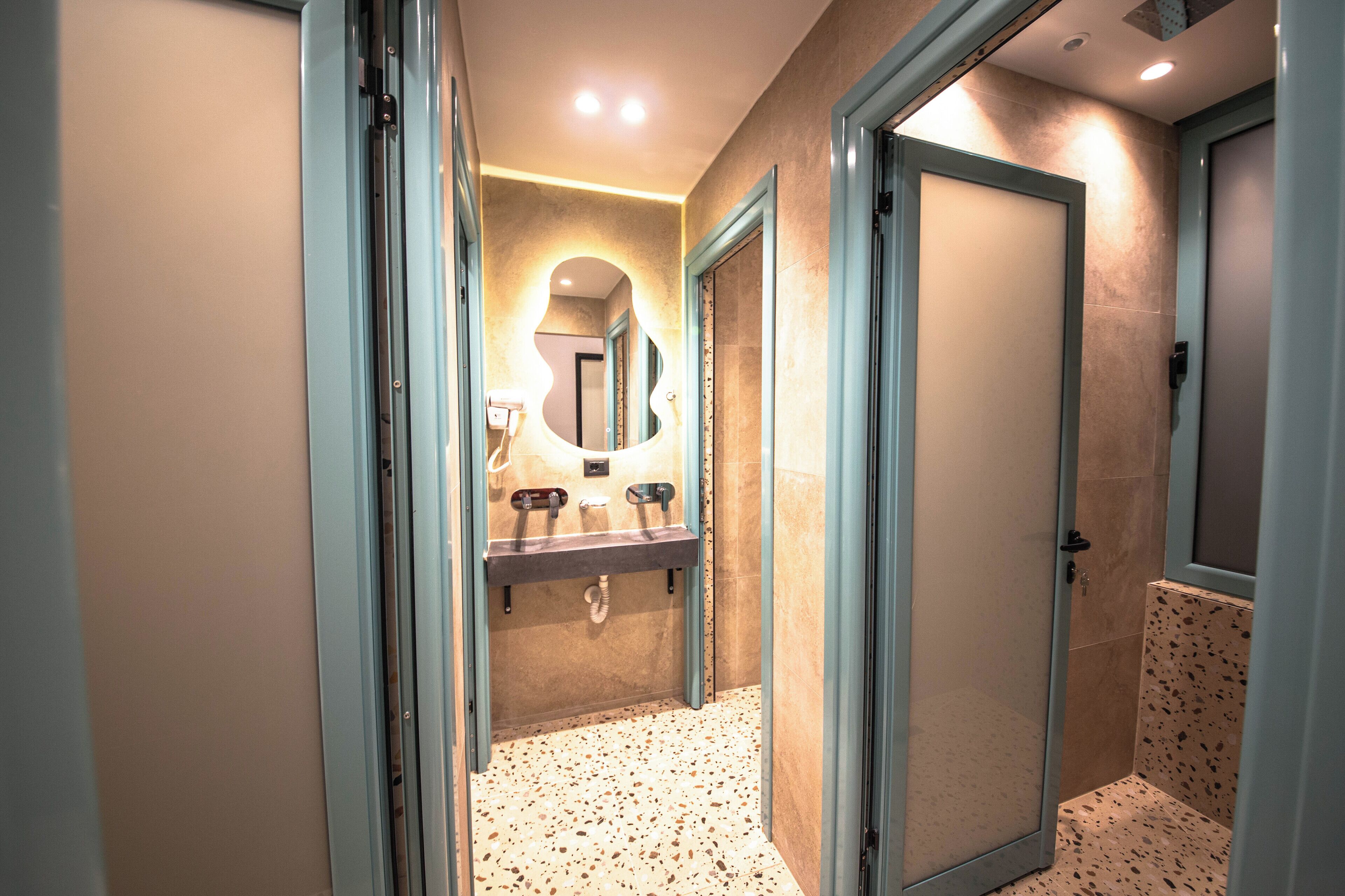 A modern bathroom with a vanity, mirror, and shower area.