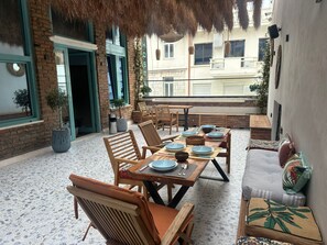 An outdoor dining area with a brick wall, wooden furniture, and potted plants. - Vega 43 Hostel (Sarande)