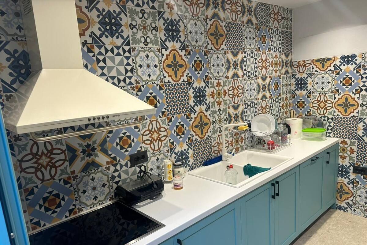 A kitchen with a patterned backsplash, a white stove, and light blue cabinets.