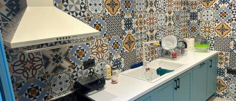 A kitchen with a patterned backsplash, a white stove, and light blue cabinets.