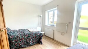 Una habitación con cama, sofá, ventana y radiador.