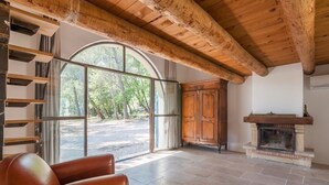 A spacious room with a large arched window, a fireplace, and a wooden ceiling. - Magnificent stone farmhouse (murs)