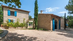 A stone house with blue shutters, a gravel driveway, and a small garden with potted plants. - Magnificent stone farmhouse (murs)
