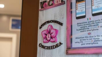 A wooden sign with 'Welcome' and 'Orchidée' text, and a flower illustration.