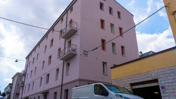 A multi-story pink building with balconies and a white van parked in front.