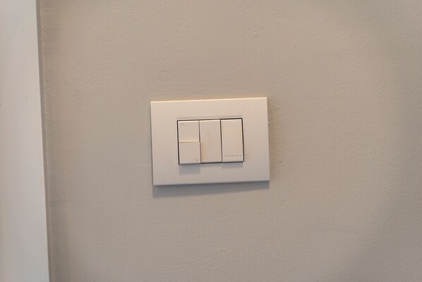 A white wall-mounted light switch. - Affittacamere Orchidea (Modena)