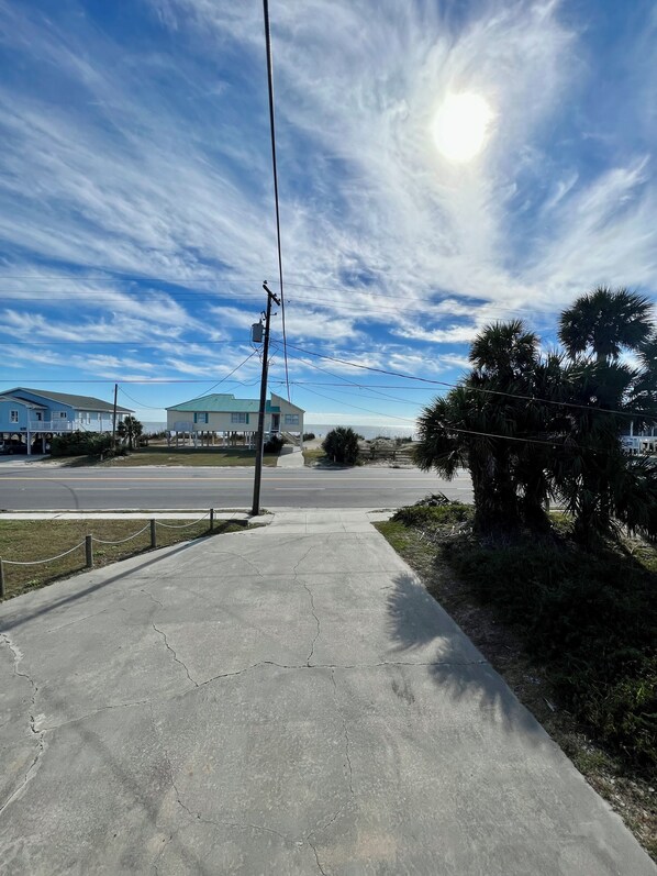 A concrete pathway leading to a residential area with houses and palm trees.