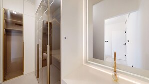 A modern room with a walk-in closet, a large mirror, and a vanity with a bottle of perfume. - Arabian Ranches 1 - Upgraded Three Bedroom Villa (Arabian Ranches)