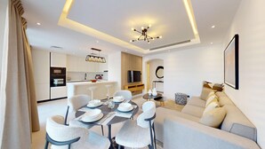 A modern living room with a dining area, a sofa, a TV, and a kitchen in the background. - Arabian Ranches 1 - Upgraded Three Bedroom Villa (Arabian Ranches)