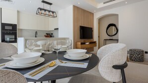 A modern dining area with a round table set for four, equipped with white plates, bowls, and gold cutlery. - Arabian Ranches 1 - Upgraded Three Bedroom Villa (Arabian Ranches)