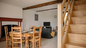Ein Essbereich mit Holztisch und Stühlen, Kamin, Sofa und Fernseher in einem Wohnzimmer.