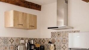 Eine moderne Küche mit Holzschränken, einer Edelstahl-Dunstabzugshaube und einer gefliesten Spritzschutzwand.