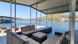Un espacio de estar al aire libre cubierto con mobiliario de mimbre y vistas al lago.