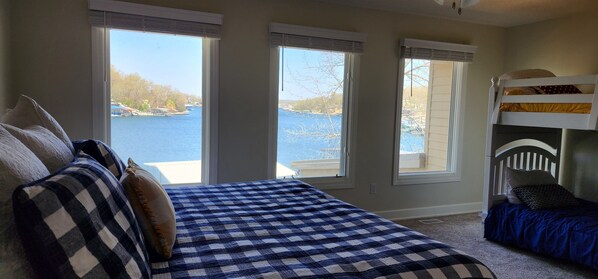 Un dormitorio con una cama grande, una litera y tres ventanas con vistas a un lago.