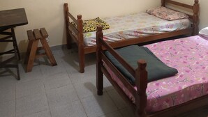 A room with two wooden beds, a small wooden table, and a bench.