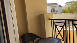 A balcony with a round table and two chairs, a railing, and a view of buildings in the background. - A charming & ideal sea view studio apartment in  ,Hurgahda with a private beach (Red Sea Governorate)
