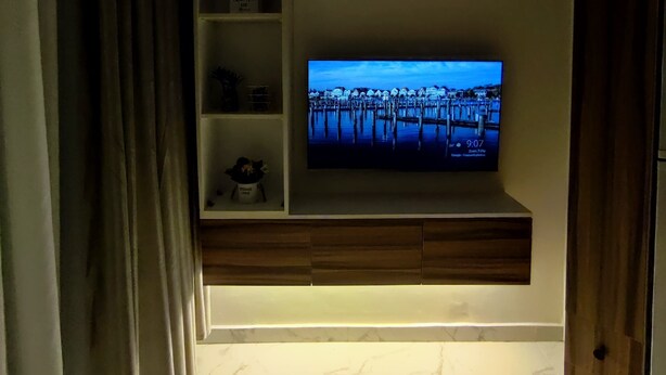 A modern living room with a flat-screen TV mounted on a wooden shelf, a built-in air conditioner, and a marble-tiled floor. - A charming & ideal sea view studio apartment in  ,Hurgahda with a private beach (Red Sea Governorate)