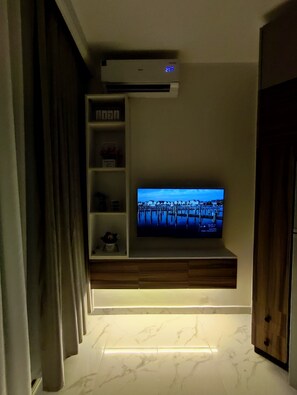 A modern living room with a flat-screen TV mounted on a wooden cabinet, a built-in air conditioner, and a marble-tiled floor. - A charming & ideal sea view studio apartment in  ,Hurgahda with a private beach (Red Sea Governorate)