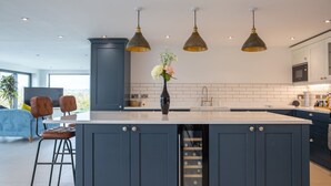 A modern kitchen with a central island, pendant lighting, and a view of the outdoors. - Beautiful Barn Conversion - Orchard Escape for 12 (Cropthorne)