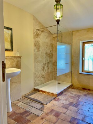Ein Badezimmer mit einem Standwaschbecken, einer Glasdusche und einer Hängelampe.