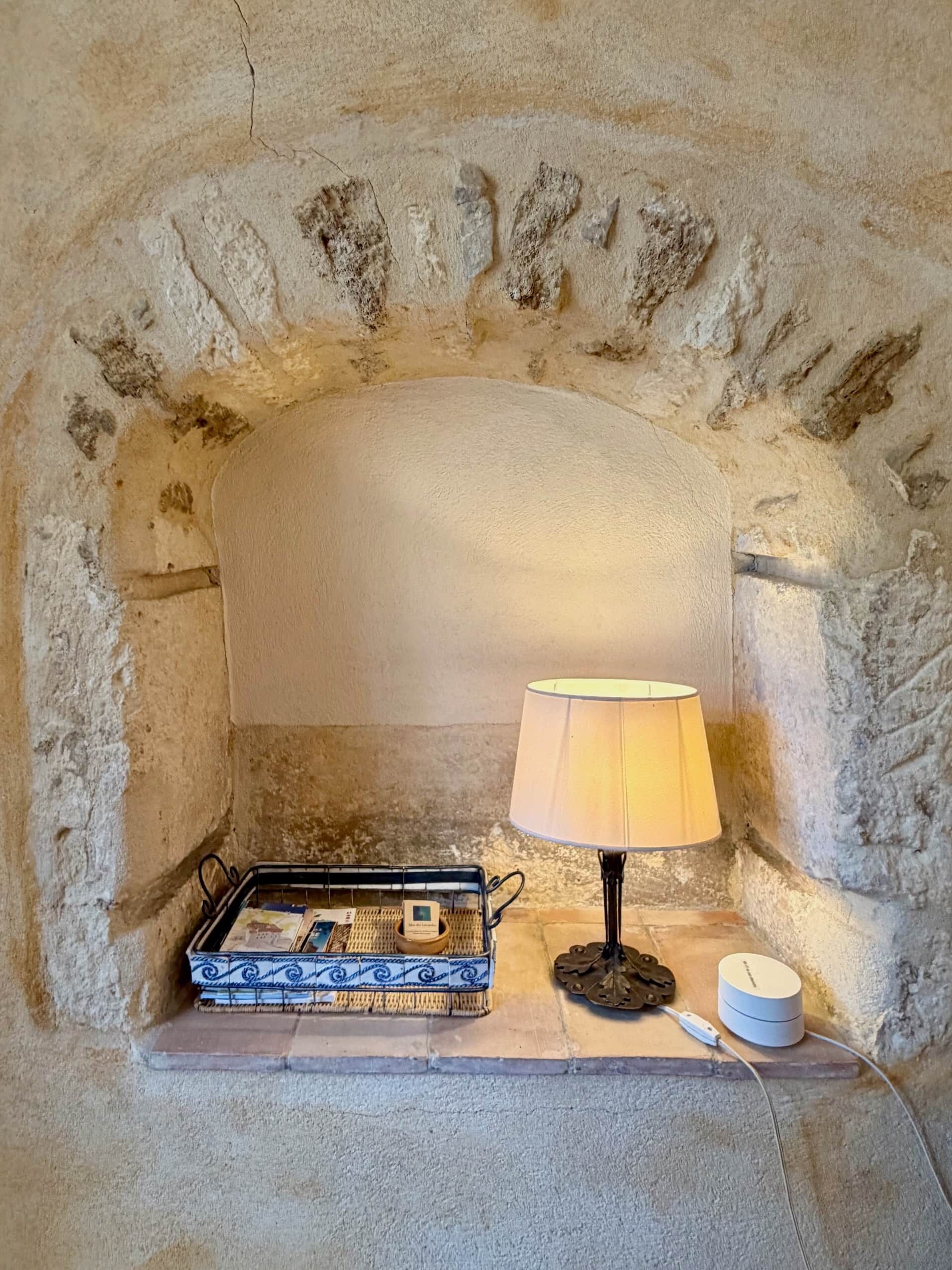 A stone fireplace with a lamp, a tray with books, and a small container.