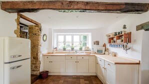 Eine Küche mit Steinwand, Holzbalken, einem Fenster und einer Spüle.