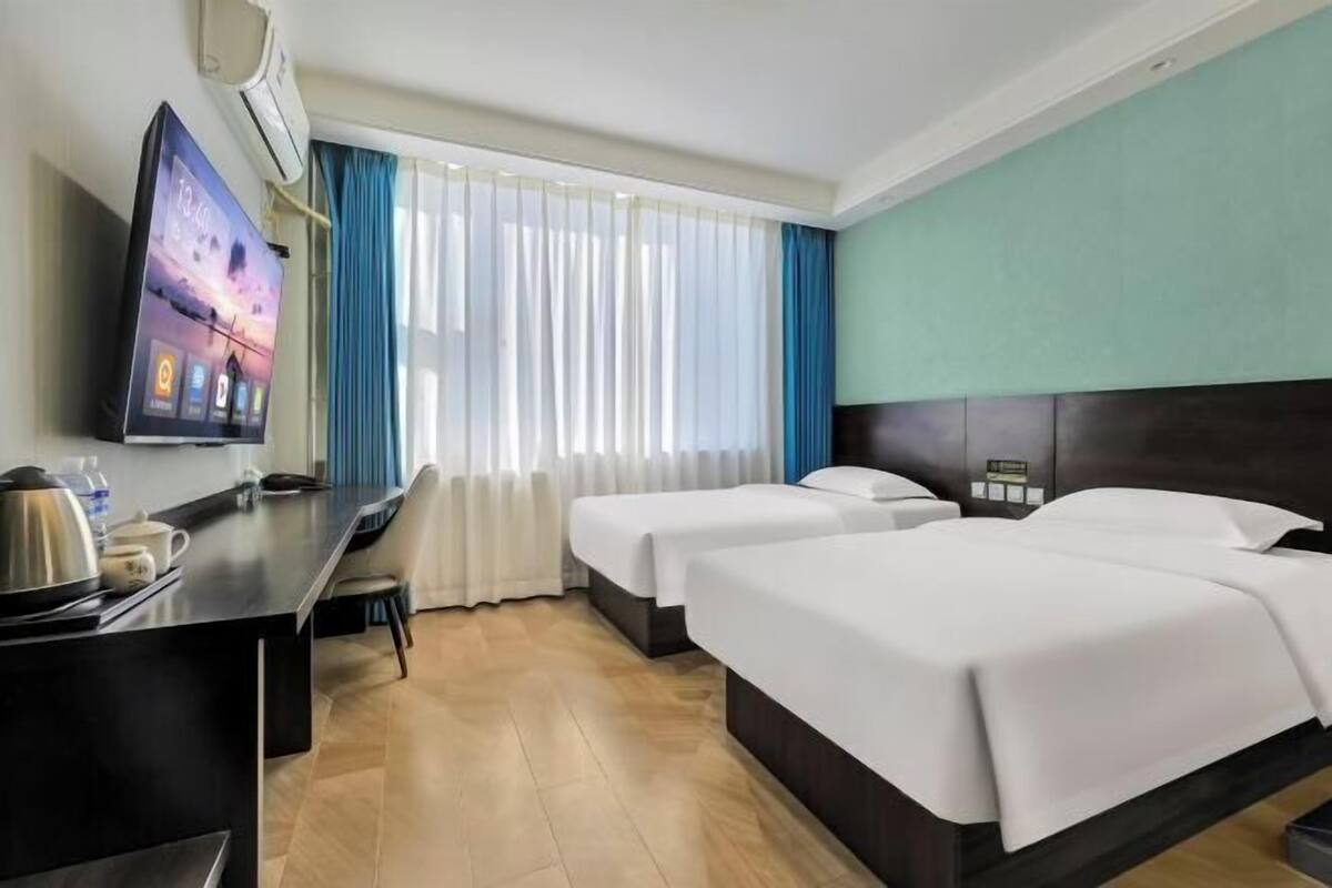 A hotel room with a bed, a desk, a TV, and a window with curtains.