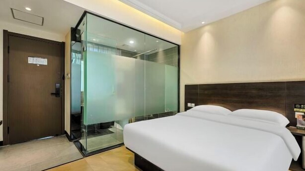 A hotel room with a large bed, a glass partition wall, and a wooden door. - Jinyuan Juntai Business Express Hotel (Shijiazhuang)