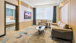 A hotel room with a bed, a sofa, a coffee table, and a TV. - Jinyuan Juntai Business Express Hotel (Shijiazhuang)
