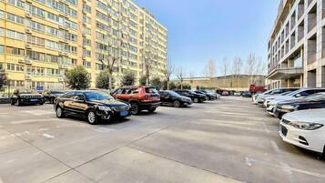 A parking lot with multiple cars parked in front of a multi-story building.