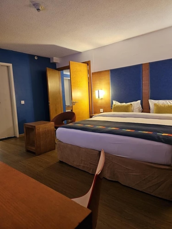 A hotel room with a bed, a desk, a chair, and a door. - AA ENTERTAINMENT HOTEL ABEOKUTA (Abeokuta)
