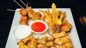 Une assiette de poulet frit, de nems et de frites, accompagnée de sauces pour tremper.
