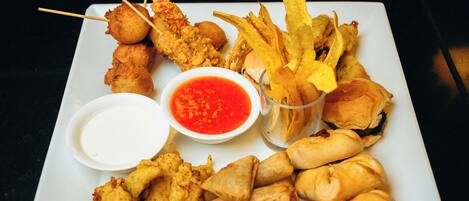 A plate of fried chicken, spring rolls, and French fries with dipping sauces.