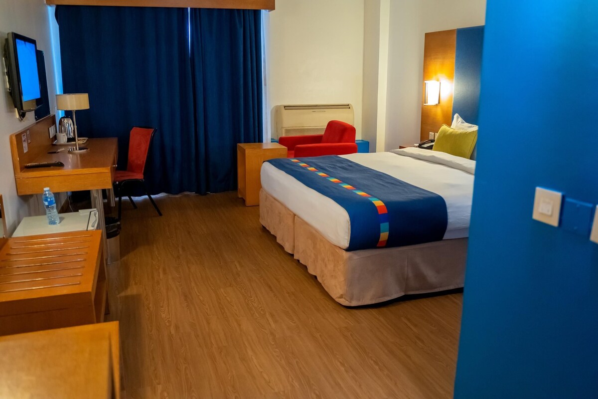Une chambre d’hôtel comprenant un lit, un bureau, une chaise, une télévision et une salle de bain.