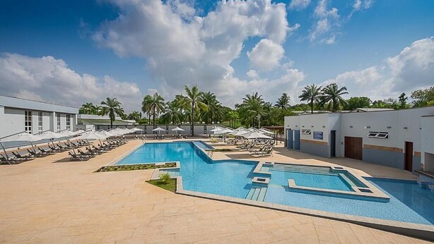 Un espace piscine comprenant plusieurs piscines, des chaises longues et des palmiers.