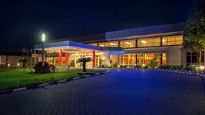 Une entrée d’hôtel moderne, dotée d’une galerie couverte, de grandes fenêtres et d’une façade bien éclairée.