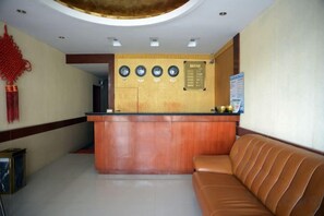 A reception area with a wooden counter, a brown leather sofa, and a wall-mounted information board. - Gao Feng Hotel (Shanghai)