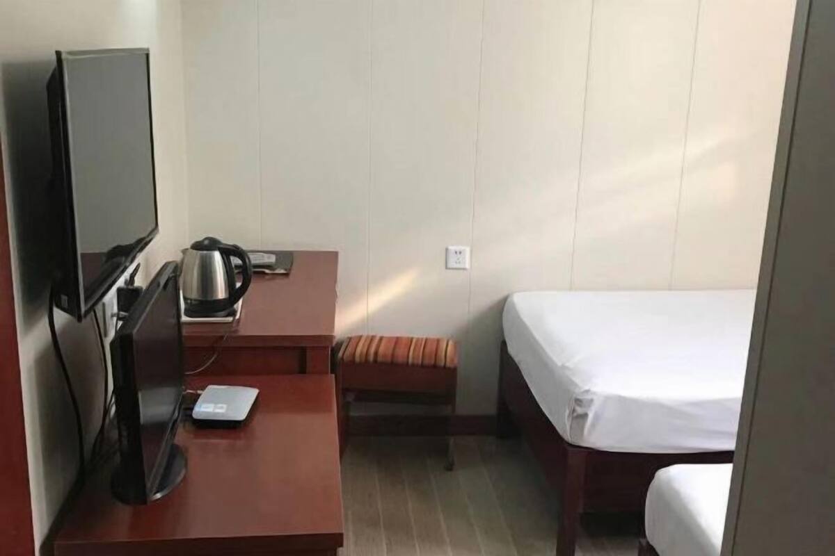 Une chambre d’hôtel comprenant un lit, un bureau avec un ordinateur, une bouilloire et une petite table.
