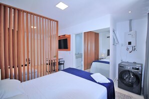 A hotel room with a bed, a washing machine, a desk, and a TV. - Studio moderno na Praia de Copa C062 (Rio de Janeiro)