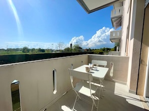 Un balcón con mesa y sillas, vistas al cielo y un paisaje lejano.