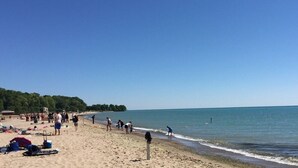A beach with people walking and swimming, a sandy shore, and a clear blue sky. - 4 Bed 1.5 Bath, 3 Story Townhouse, Free Parking (Milwaukee)