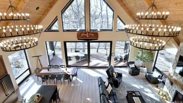 A spacious living area with a high ceiling, large windows, and a chandelier. - Modern Cabin, Cozy and Peaceful (Lake Geneva)
