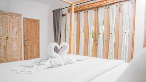 A bedroom with a bed, wooden wardrobe, and curtains. - Bali Invest Living (Tumbak Bayuh)