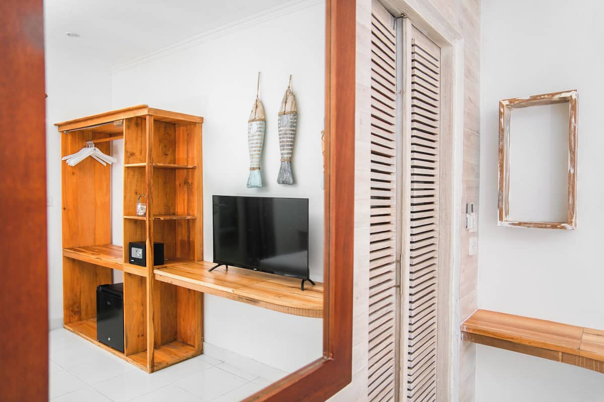 A room with a wooden wardrobe, a flat-screen TV, and two decorative items on the wall.