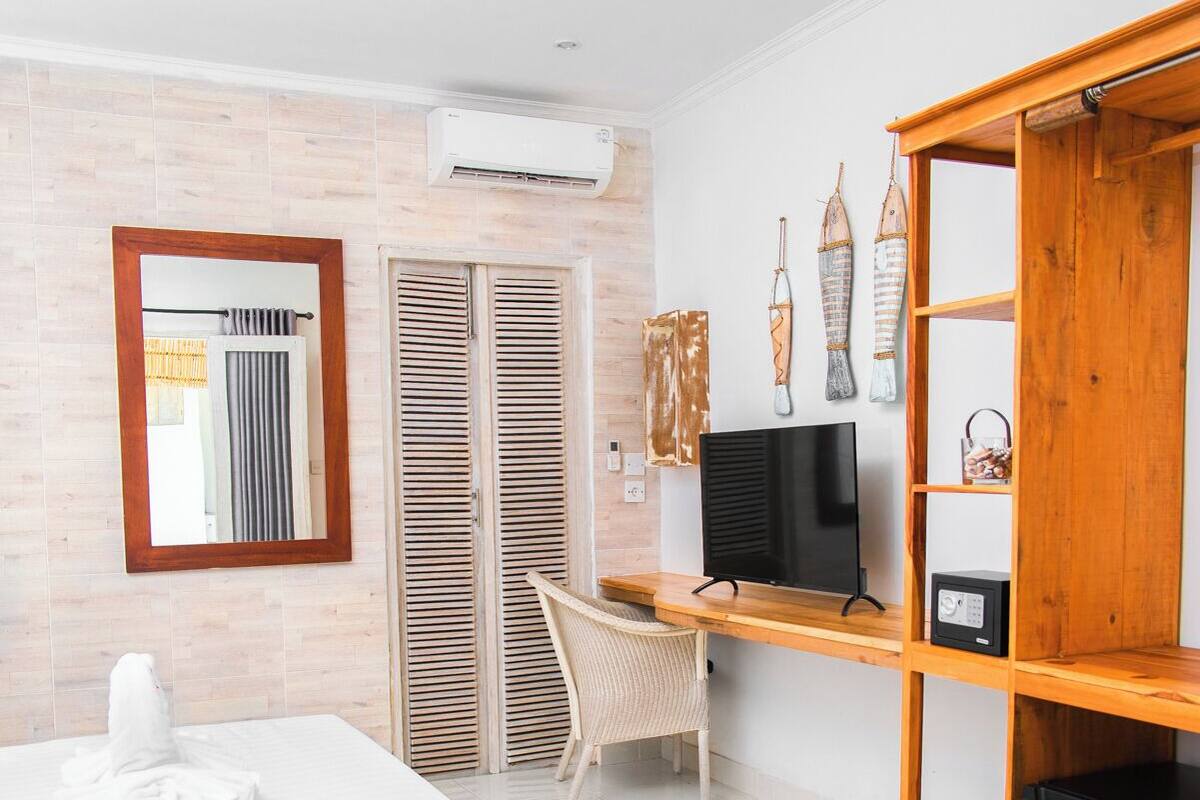 A modern bedroom with a wooden bed, a desk with a TV, a wardrobe, and a mirror on the wall.