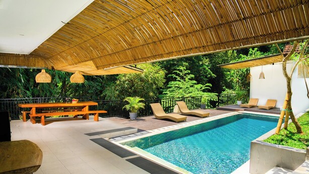 A pool area with lounge chairs, a wooden bench, and a thatched roof structure. - Bali Invest Living (Tumbak Bayuh)